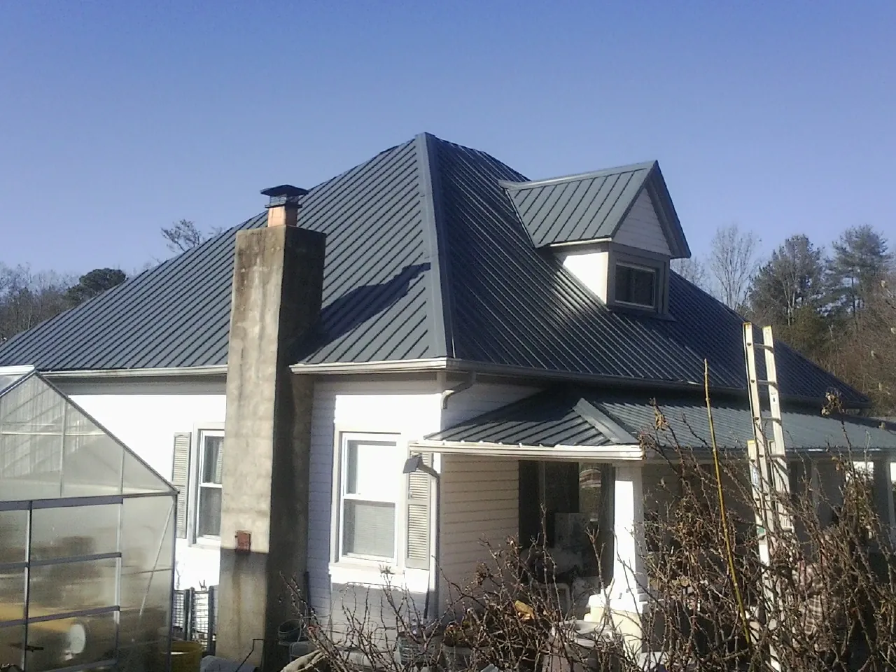Dark blue standing seam metal roof on a white farmhouse with dormer — Slate & Tile Roof Repair by Roofing Brothers in Oradell