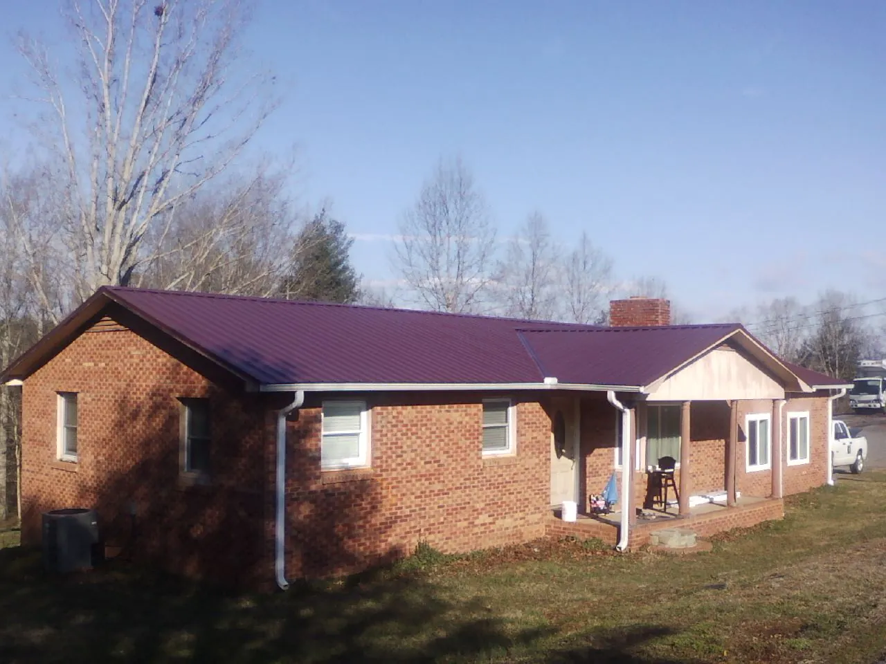 Burgundy metal roof on a brick ranch home with a new addition in Oradell