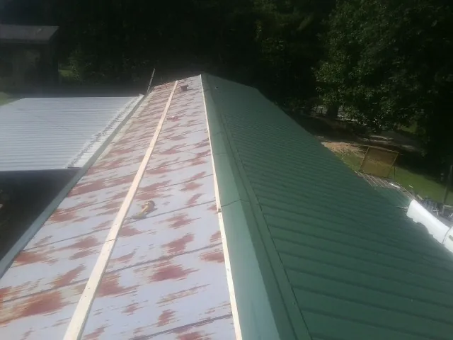 Old rusted panels beside newly installed green metal roofing — Wind Damage Roof Repair by Roofing Brothers in Oradell