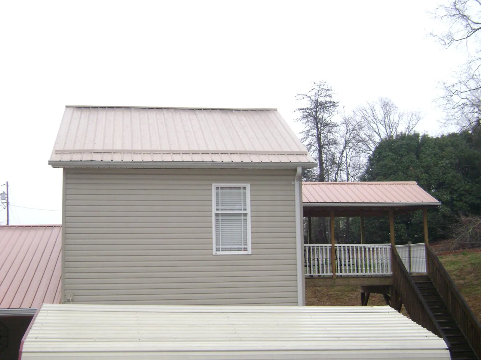 Tan metal roofs on a two story addition and attached porch, from a Roof Replacement job in Oradell