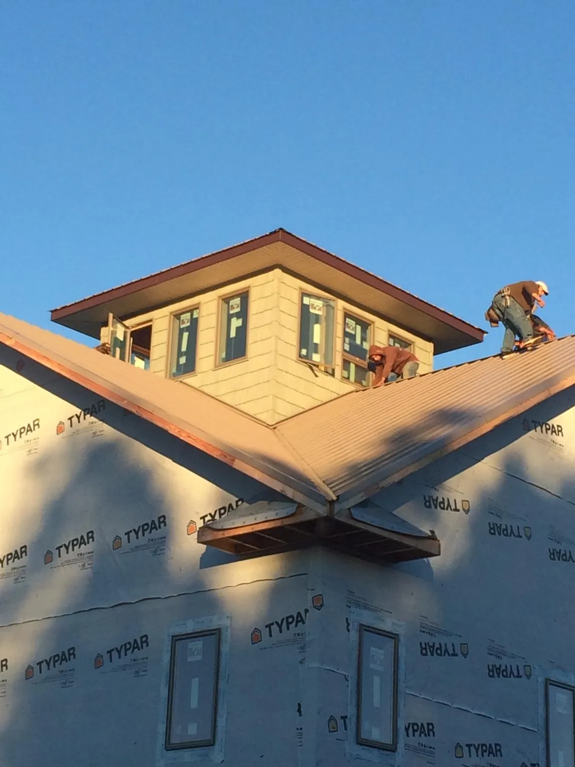 Roofers working around a rooftop cupola on a new metal roof at sunset — Roof Waterproofing in Oradell by Roofing Brothers